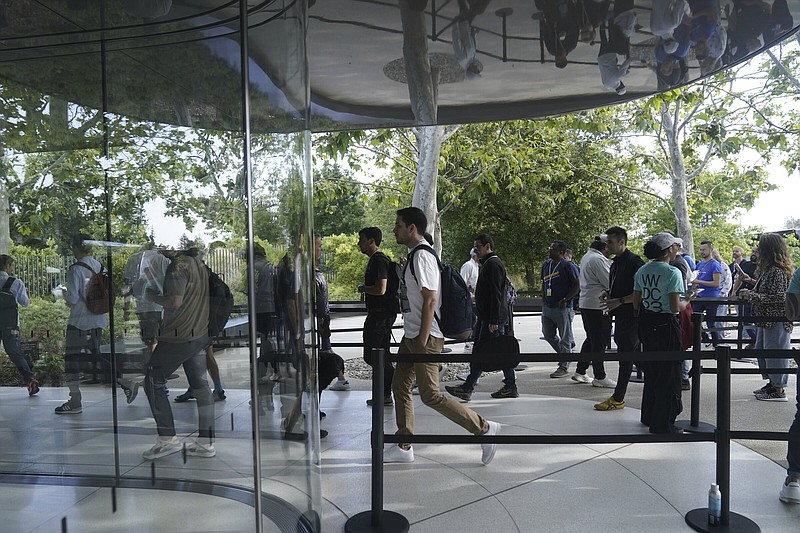 People are reflected as they enter a building Monday, June 5, 2023, before an announcement on new products on the Apple campus in Cupertino, Calif. (AP Photo/Jeff Chiu)