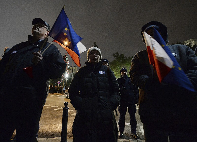 FILE - Men with Poland and European Union flags take part in a protest outside Poland's parliament building as lawmakers voted to approve the much-criticized legislation that allows politicians to fire judges who criticize their decisions, in Warsaw, Poland, on Jan. 23, 2020. The European Union stepped up its rule-of-law fight with member state Poland on Monday, June 5, 2023, when the bloc's highest court confirmed that Warsaw had refused to comply with EU rules on judicial independence for which it has already lost over half a billion euros in fines. (AP Photo/Czarek Sokolowski)