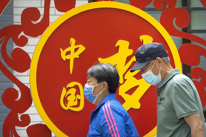 File - People wearing face masks walk past a propaganda billboard reading "China Dream" at a public park in Beijing, Thursday, May 11, 2023. The global economy is likely slowing sharply this year, hobbled by high interest rates, the repercussions of Russia's invasion of Ukraine and the lingering effects of the coronavirus pandemic according to the latest outlook of the World Bank. (AP Photo/Mark Schiefelbein, File)