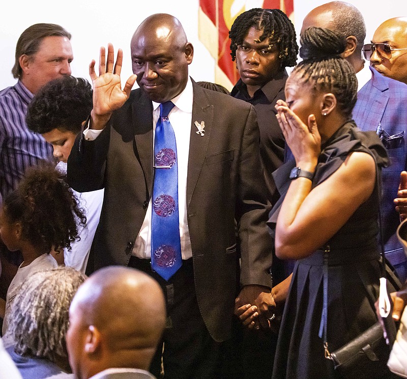 Civil Rights Attorney Ben Crump, center, waves to members of the community walking out  holding the hand of Pamela Dias, the mother of Ajike "AJ" Owens, following a press conference, Wednesday afternoon, June 7, 2023 at the New St. John Missionary Baptist Church in Ocala, Fla. Susan Louise Lorincz, 58, who is accused of fatally shooting Owens last week in the violent culmination of what the sheriff described as a 2 and a half year feud was arrested Tuesday, June 6, the Marion County Sheriffs Office said. (Doug Engle/Ocala Star-Banner via AP)