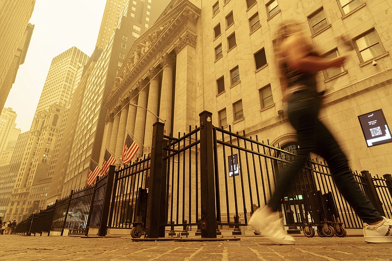 A pedestrian walks past the smoke and haze shrouded New York Stock Exchange building in New York City Wednesday, June 7, 2023. Intense Canadian wildfires are blanketing the northeastern U.S. in a haze, turning the air acrid and the sky yellowish gray. (AP Photo/J. David Ake)