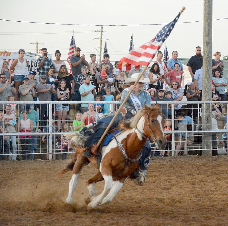 Graham Thomas/Herald-Leader
ACRA Queen Chesney Grimes rides with the American Flag during the national anthem at the 2022 Siloam Springs Rodeo.