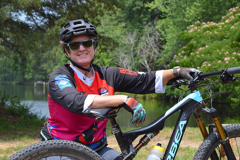Northwoods Trails Coordinator Traci Berry has her photo taken with her bike in one of the scenic areas that is part of the trail system. In addition to managing the trail system, Berry is also a mountain biking enthusiast. - Photo by Donald Cross of The Sentinel-Record