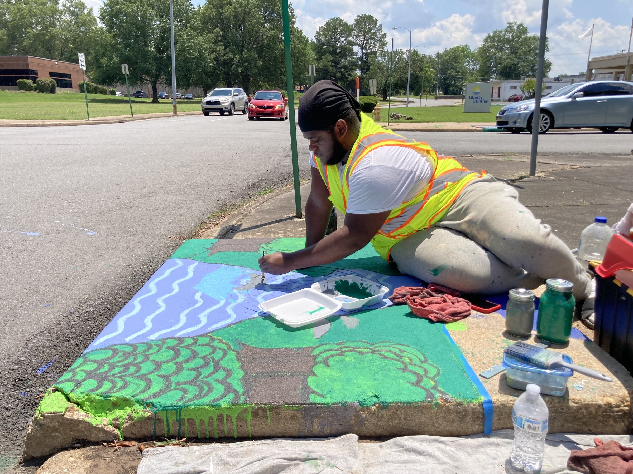 Artist at work on storm drain mural