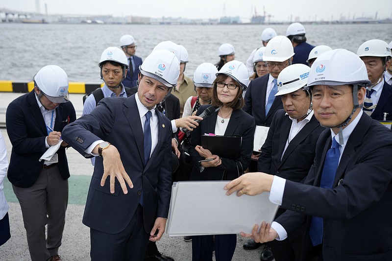 U.S. Secretary of Transportation Pete Buttigieg (front left) is guided to the Yokohama Port during a tour which includes a visit to a construction site for a new pier that will accommodate larger ships coming from the U.S. on Monday, June 19, 2023, in Tokyo. (AP Photo/Eugene Hoshiko)