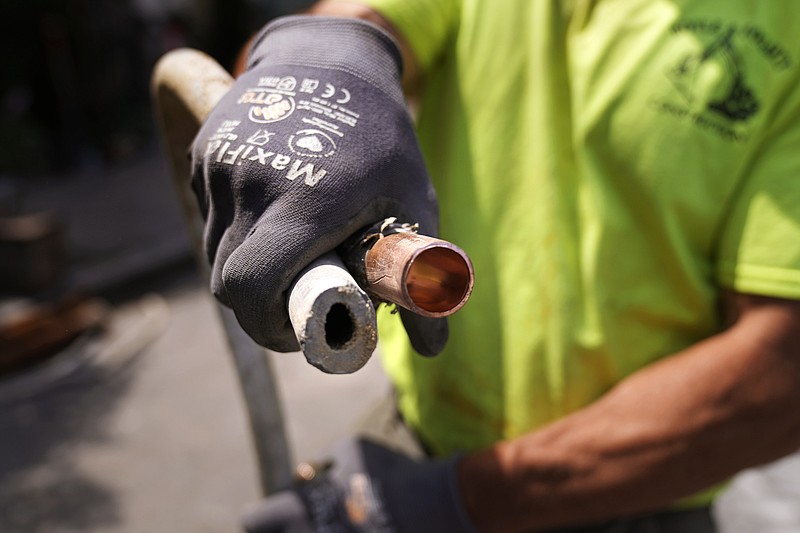 Richie Nero, of Boyle & Fogarty Construction, shows the the cross section of an original lead residential water service line (left) and the replacement copper line on June 29 outside a home where service was being upgraded in Providence, R.I. 
(AP/Charles Krupa)