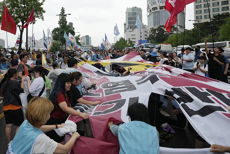 Protesters tear a flag with an image symbolizing nuclear on the Japanese rising sun flag during a rally against Japanese government's plan to release treated radioactive water from Fukushima nuclear power plant, near a building which houses Japanese Embassy in Seoul, South Korea, Saturday, July 15, 2023. The red sign reads "Treated radioactive water from Fukushima." (AP Photo/Ahn Young-joon)