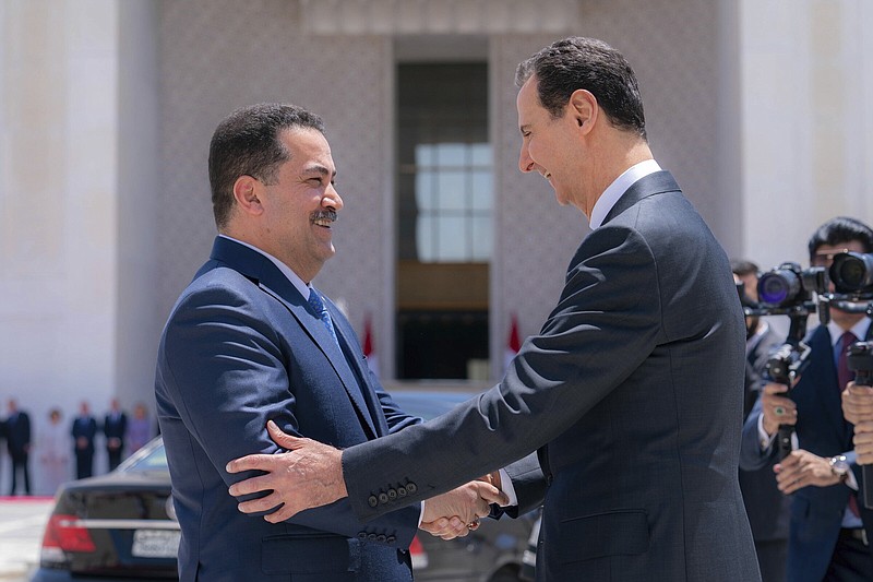 In this photo released by the Syrian official news agency SANA, Syrian President Bashar Assad, right, welcomes Iraq's Prime Minister Mohammed Shia al-Sudani before review a military honour guard during a welcome ceremony in Damascus, Syria, Sunday, July 16, 2023. Iraq's prime minister held talks Sunday with Syrian President Bashar Assad in Damascus during the first such trip by an Iraqi premier to the war-torn country since the 12-year conflict began. (SANA via AP)