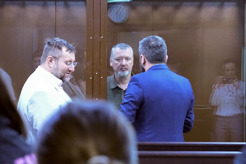 Igor Girkin, centre, also know as Igor Strelkov, the former military chief for Russia-backed separatists in eastern Ukraine speaks with his lawyer standing in a glass cage in a courtroom at the Moscow's Meshchansky District Court in Moscow, Russia, Friday, July 21, 2023. A prominent Russian hard-line nationalist who accused President Vladimir Putin of weakness and indecision in Ukraine was detained Friday on charges of extremism, a signal the Kremlin has toughened its approach with hawkish critics after last month's abortive rebellion by the Wagner mercenary company. (AP Photo/Alexander Zemlianichenko)