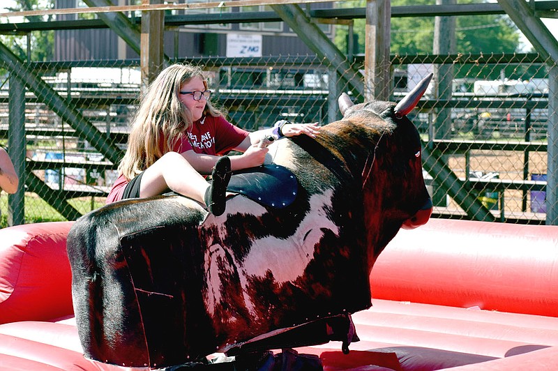 MARK HUMPHREY  ENTERPRISE-LEADER/Getting on is half the battle when riding a mechanical bull. The attraction, new for this year's Lincoln Rodeo, proved a big draw for girls and boys alike.
