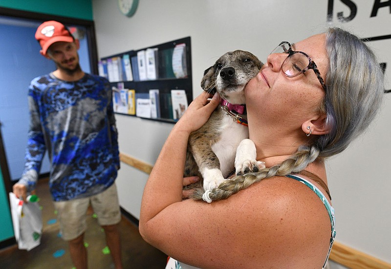 Brittany Martin of Madison County smiles Tuesday as she holds her new puppy, Lilith, after completing her adoption paperwork as Martin's brother, Dilon Gulledge, watches inside the city of Fayetteville Animal Services shelter in Fayetteville.(NWA Democrat-Gazette/Andy Shupe)