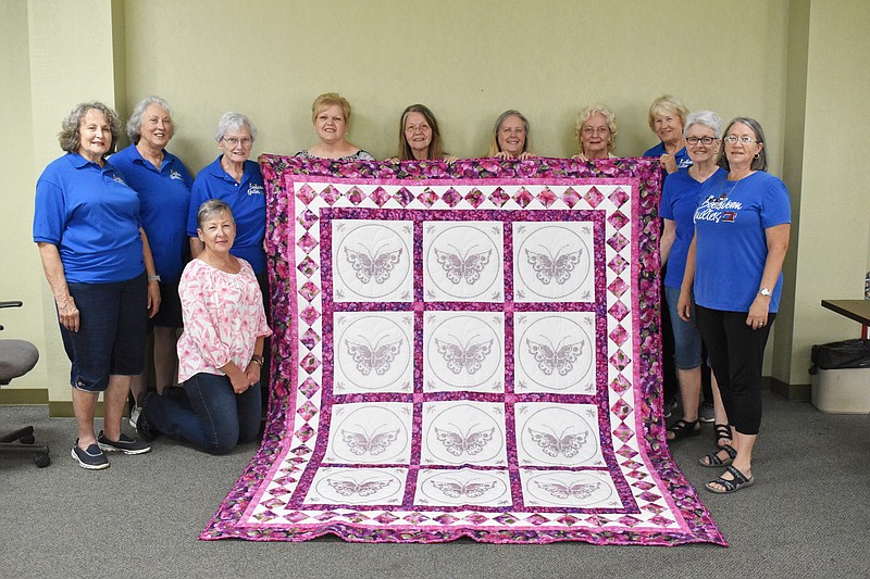 Democrat photo/Garrett Fuller — People who helped the Bookworm Quilters create a quilt to auction off at the Moniteau County Fair to benefit the California Nutrition Center and Quilts of Valor pose Thursday with their creation in Heyssel Hall at the Moniteau County Library. Pictured, from left, are: Sally Vogel, Joyce Crook, Roberta Rothstein (kneeling), Darlene Matthews, Beverly Kleffner, Pam Zimmerman Jo Ann Bestgen, Dorothy Hise, Judy Scott, Mary Haldiman and Rita Rippee. Not pictured is Sharon Elder. The quilt will be auctioned at 7 p.m. tonight before the rodeo in the main arena at the Moniteau County Fairgrounds.