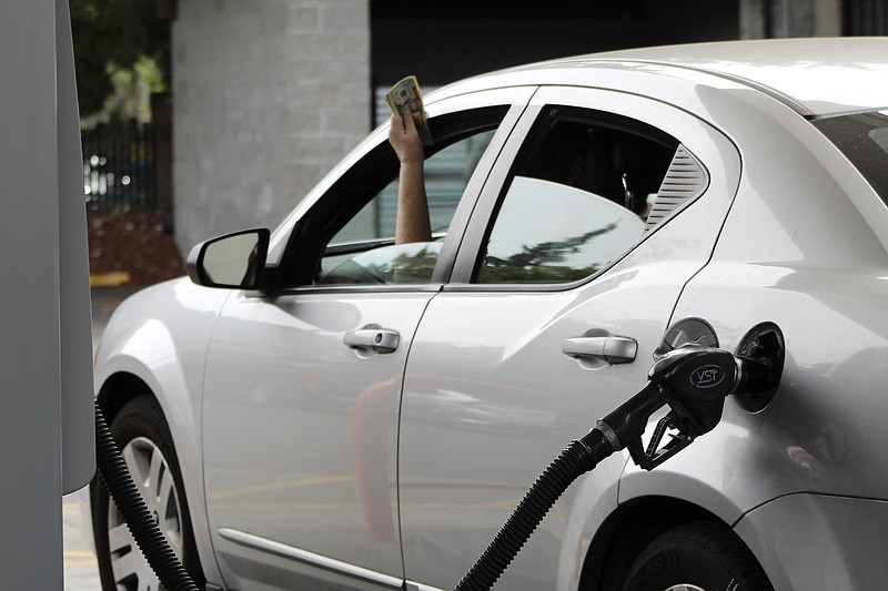 A driver holds cash out of the window of their car while waiting to pay a gas station attendant to pump their gas, Friday, Aug. 4, 2023, in Portland, Ore. Oregon drivers can now pump their own gas for the first time since the 1950s, after Gov. Tina Kotek signed a bill allowing people across the state to choose between having an attendant pump their gas or doing it themselves. (AP Photo/Claire Rush)