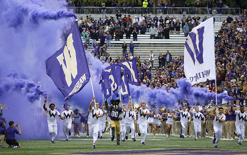 Washington cheerleaders and Harry, the Husky mascot, set off smoke effects as they lead the team out of the tunnel at Husky Stadium for Washington's home opener against Montana Sept. 9, 2017, in Seattle. - Photo by Ted S. Warren of The Associated Press