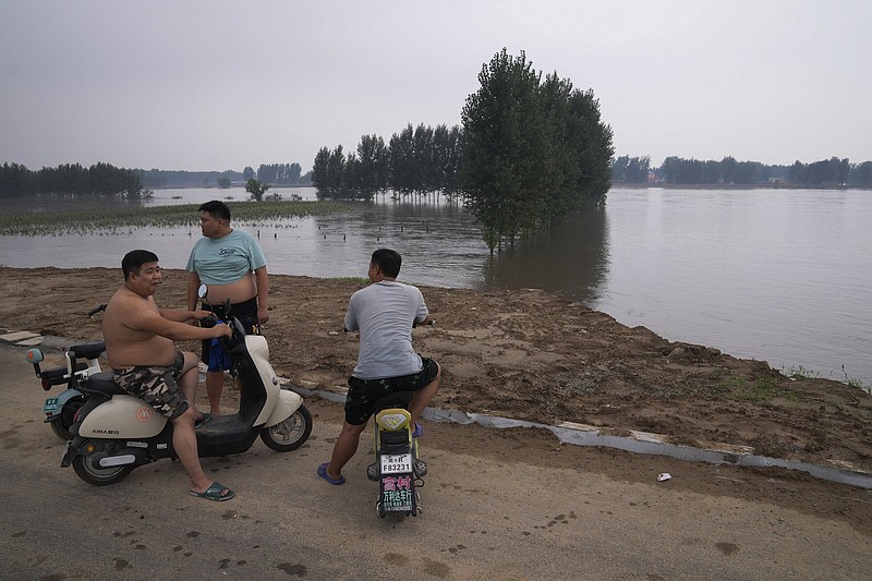 Villagers look over a swollen river which floods the crops at a village in Langfang in Hebei province, China Wednesday, Aug. 2, 2023. (AP Photo/Andy Wong)