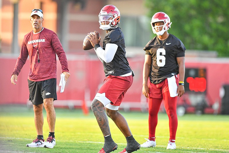 Arkansas quarterback KJ Jefferson (1) passes as teammate Jacolby Criswell (6) and offensive coordinator Dan Enos look on Friday during the Razorbacks first practice of fall camp at the Fred W. Smith Football Center in Fayetteville. - Photo by Hank Layton of NWA Democrat-Gazette