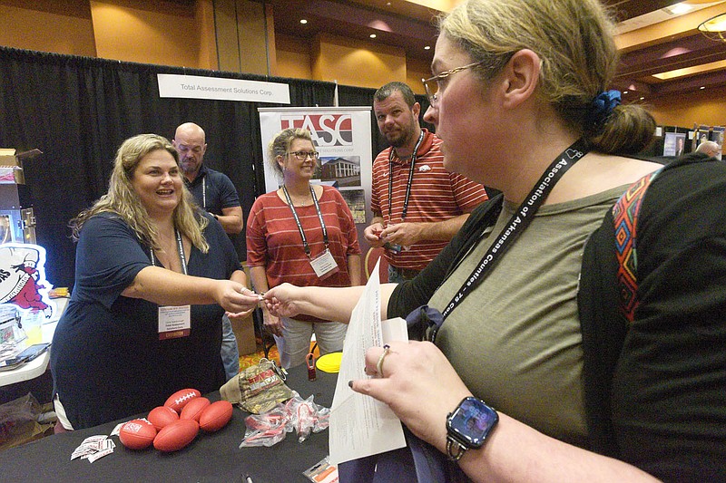 Corie Scarborough (left) with Total Assessment Solutions hands out souvenirs Wednesday during opening day of the Association of Arkansas Counties convention in Rogers. Benton County is hosting the gathering this year. The convention runs through Friday at the Rogers Convention Center. Activities include break-out sessions for various county office holders, general meetings, classes, an exhibit hall and a fish fry. Go to nwaonline.com/photos for todays photo gallery.

(NWA Democrat-Gazette/Flip Putthoff)