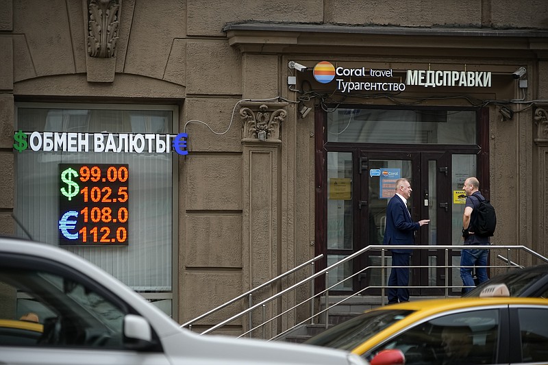 Two men talk to each other at the entrance of a currency exchange office in Moscow, Russia, Monday, Aug. 14, 2023. Russia&#x2019;s central bank made a big interest rate hike of 3.5 percentage points on Tuesday, Aug. 15, 2023, an emergency move designed to fight inflation and strengthen the ruble after the country's currency reached its lowest value since early in the war with Ukraine. (AP Photo/Alexander Zemlianichenko)