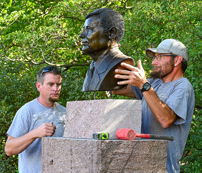 Julie Smith/News Tribune photo: 
Aaron Carrender, left, looks closely at which way Nate Conner needs to adjust the lifesize bronze bust of Mel Carnahan onto its base. The bust of the two-term Missouri governor was installed Wednesday, Aug. 16, 2023, onto a base that was placed two weeks ago in the northeast corner of the Governor's Garden in Jefferson City. The garden was renamed Carnahan Memorial Garden following the death of Carnahan, who was killed in a plane crash on October 16, 2000, while campaigning on  for a congressional seat.