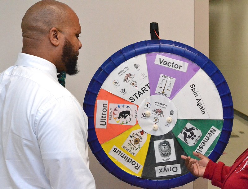 Thaddeus Pearson, assistant principal of Pine Bluff Junior High School, shows a student what team she will be placed on after spinning the wheel during the first day of school Wednesday. (Pine Bluff Commercial/I.C. Murrell)