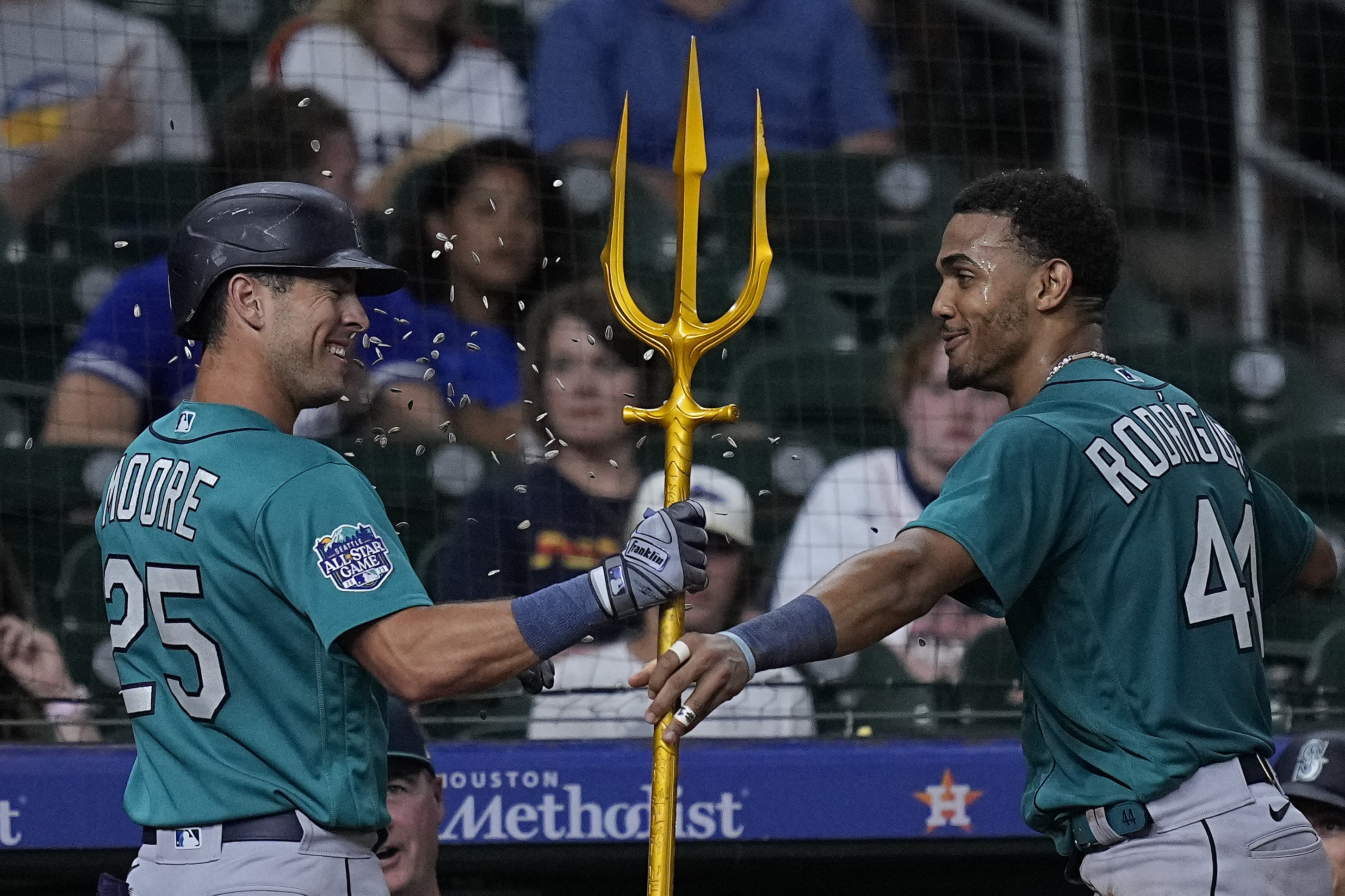 Seattle Mariners' Teoscar Hernandez holds a trident in the dugout