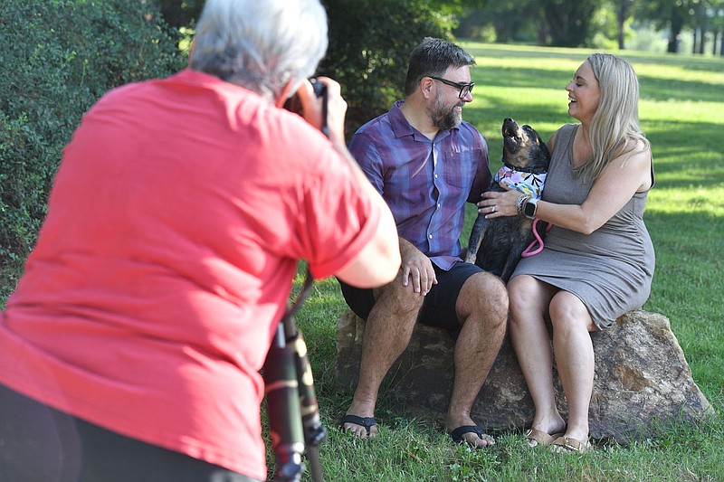 Mickey Arlow (left), a photographer with Animal House Studio Photography in Bella Vista, makes a portrait Thursday, Aug. 24, 2023, of Gracie and Mike Ziegler and their dog, Otter, for the Humane Society of the Ozarks benefit book ‘Tales of Love in Gulley Park in Fayetteville. The citys Parks and Recreation Advisory Board is in the middle of trying to jumpstart a “friends of” group that would help raise money to develop parks in the city. Visit nwaonline.com/photo for today's photo gallery. 
(NWA Democrat-Gazette/Andy Shupe)
