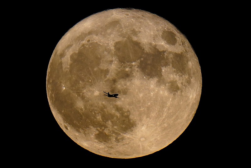 FILE - A plane passes in front of a supermoon, July 13, 2022, in Milwaukee. A rare blue supermoon could normal raise tides just as Hurricane Idalia takes aim at Floridas west coast, exacerbating flooding from the storm. The moon will be closest to the Earth on Wednesday night, Aug. 30, 2023, the same day Idalia is expected to make landfall in Florida. (AP Photo/Morry Gash, File)