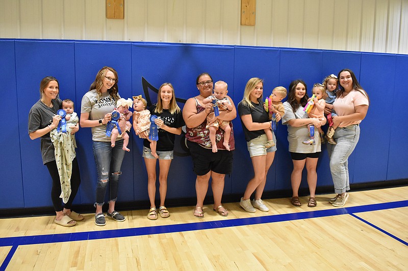 Democrat photo/Garrett Fuller — Winners of the High Point Homecoming baby contest are seen Saturday in the High Point R-III School gymnasium. Pictured, from left, are: Dane Elkins, winner of the 0-6 boys category; Parker Schnieders, winner of the 0-6 girls category, held by mother Ashley Benton; Effie Kueffer, winner of the 7-12 girls category, held by mother Lizzy Kirby; Brantley Rissler, winner of the 7-12 boys category, held by Amanda Rissler; Walker Roling, winner of the 13-24 boys category, held by mother Ally Roling; Dally Steenbergen, winner of the 13-24 girls category, held by mother Kendra Steenbergen; and IdaMae Bond, runner-up winner of the 13-24 girls category, held by mother Cheyenne Colter Bond.