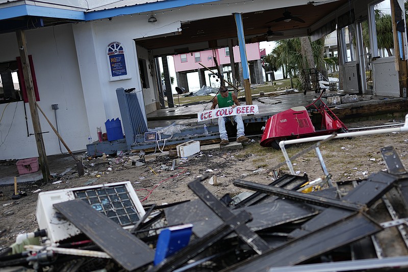 A man picks up a sign amid debris of a storm-damaged business in Horseshoe Beach, Fla., Thursday, Aug. 31, 2023, one day after the passage of Hurricane Idalia. (AP Photo/Rebecca Blackwell)