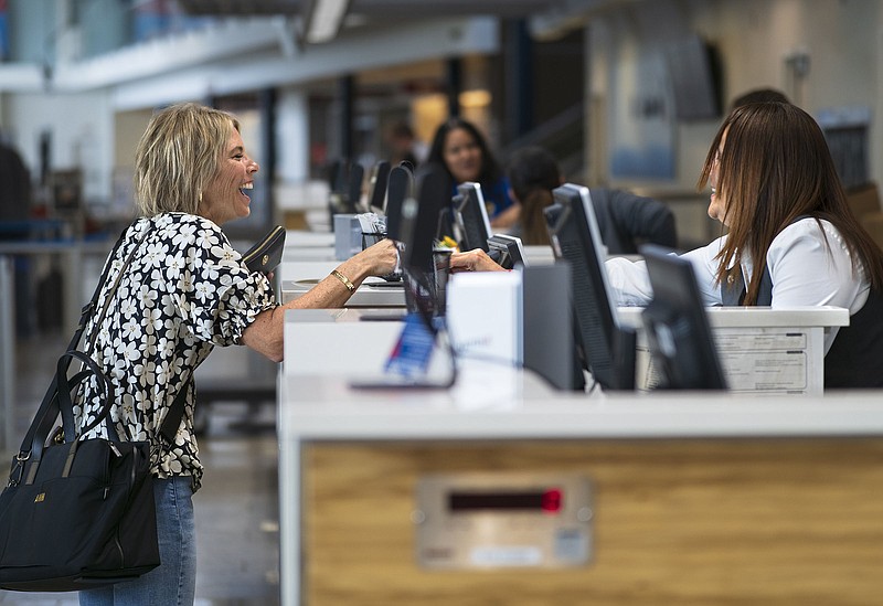 Andrea Morris of Fayetteville (left) reacts as she receives her boarding pass from Delta ticket agent Lorenna White on Sept. 7 at Northwest Arkansas National Airport in Highfill. The airport's board voted Tuesday to begin the process of detaching from Highfill. Visit nwaonline.com/photos for today's photo gallery.

(File Photo/NWA Democrat-Gazette/Charlie Kaijo)