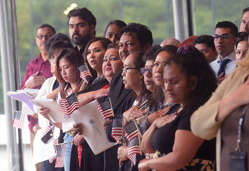 New U.S. citizens take the Oath of Allegiance on Tuesday during naturalization proceedings in the Great Hall at Crystal Bridges Museum of American Art in Bentonville. Go to nwaonline.com for todays photo gallery.

(NWA Democrat-Gazette/Flip Putthoff)