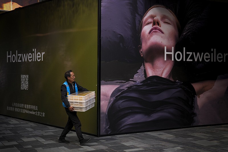 A delivery worker walks by a foreign fashion storefront under renovation at an outdoor shopping mall in Beijing Wednesday, Sept. 20, 2023. Leading Chinese planners voiced confidence Wednesday in the outlook for the world's second-largest economy, holding key interest rates steady amid signs of improvement in some areas such as services. (AP Photo/Andy Wong)
