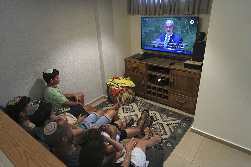 Avigad Tovim, center, and his family watch a live televised broadcast of Prime Minister Benjamin Netanyahu speaking ay the United Nations General Assembly, in Kibbutz Saad in southern Israel near the Gaza border, Friday, Sept. 22, 2023. (AP Photo/Tsafrir Abayov)