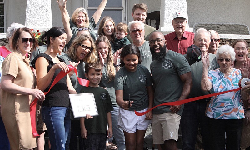 Democrat photo/Evan Holmes:  
Center, Erin and Aaron Clark cut the ribbon to their new business the Factory at Potato Chip with their two kids. Members of the California Area Chamber of Commerce surround the family as part of the venue's grand opening.
