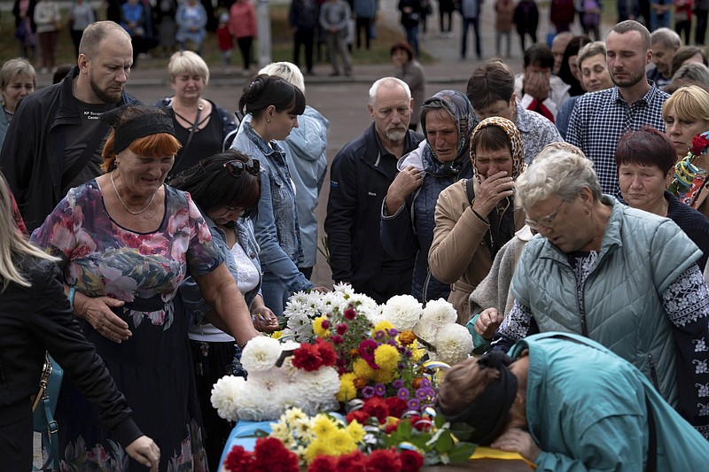 Local residents come to pay their respects to a Ukrainian soldier, Andrii "Adam" Grinchenko of the 3rd Assault Brigade, who was injured in the battle for Andriivka during a funeral ceremony in Shostka, Sumy region, Ukraine, Tuesday, Sept. 26, 2023. Hundreds of people came to say goodbye to the 31-year-old soldier Grinchenko in his hometown of Shostka. (AP Photo/Roman Hrytsyna)