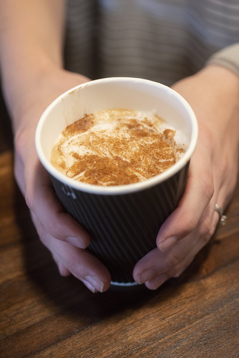 Ashtyn Leinbach, owner of Perisseia Coffeehouse in Siloam Springs, holds a latte with cinnamon Friday Sept. 22, 2023. Visit nwaonline.com/photo for today's photo gallery.   (NWA Democrat-Gazette/J.T. Wampler)