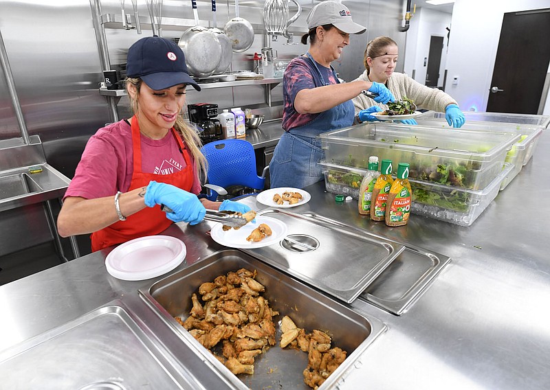 Alyssa Brasuell (from left) works Thursday alongside Melissa Hoeldtke and Brynne Larson to assemble meals while volunteering in the cafe inside the Samaritan Community Center in Rogers. The center has experienced an increase in the need for food assistance within the population it serves. Visit nwaonline.com/photo for todays photo gallery.

(NWA Democrat-Gazette/Andy Shupe)