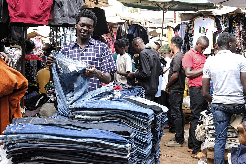 A second hand clothes retailer folds second hand jeans at his stall at Owino Market in Kampala, the capital of Uganda,Friday Sept. 15, 2023. Downtown Kampala&#x2019;s Owino Market has long been a go-to enclave for rich and poor people alike looking for affordable but quality-made used clothes, underscoring perceptions that Western fashion is superior to what is made at home. But, despite their popularity, secondhand clothes are facing increasing pushback. (AP Photo/Hajarah Nalwadda)