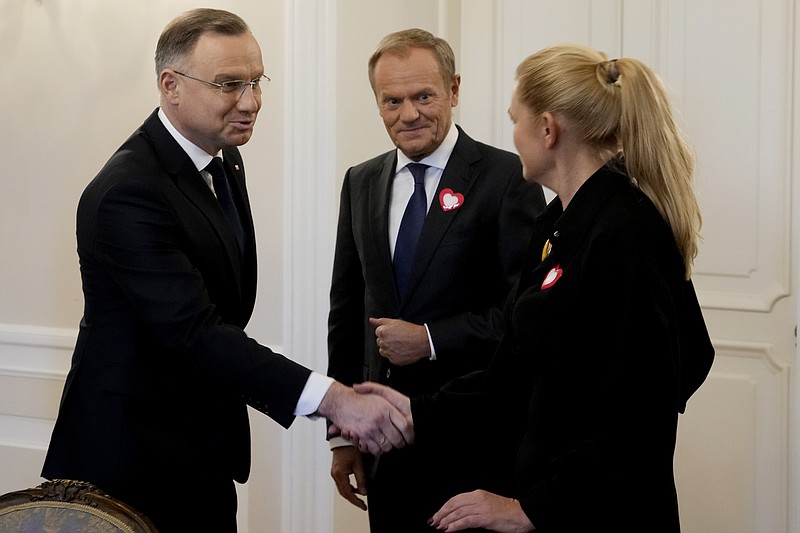 Poland's President Andrzej Duda, left, shakes hands with opposition party member Barbara Nowacka, right, as the top opposition leader Donald Tusk looks on, at the presidential palace in Warsaw, Poland, on Tuesday, Oct. 24, 2023. Duda on Tuesday opened two days of consultations with the heads of political groups that won seats in parliament in the national election on Oct. 15. The leaders of the opposition parties that collectively won the most votes in Poland's recent elections announced Tuesday that Donald Tusk, the leader of the largest group, is their candidate to be prime minister and that they want to get to work as soon as possible. But they must wait for Duda to decide the next steps. (AP Photo/Czarek Sokolowski)