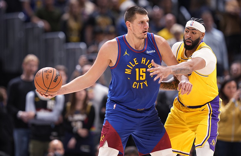 Denver Nuggets center Nikola Jokic, left, looks to pass the ball as Los Angeles Lakers forward Anthony Davis defends during the first half of an NBA basketball game Tuesday, Oct. 24, 2023, in Denver. (AP Photo/David Zalubowski)
