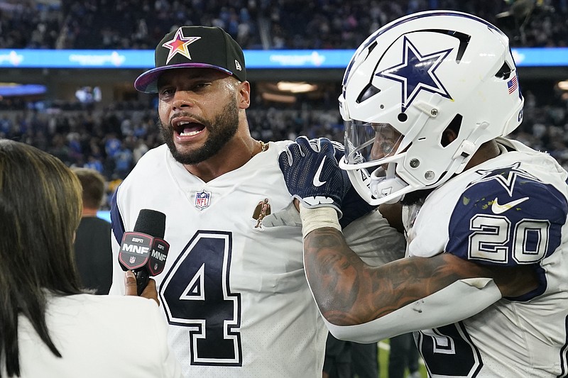 Dallas Cowboys quarterback Dak Prescott (4) and running back Tony Pollard (20) hug during a postgame interview after an NFL football game against the Los Angeles Chargers, Monday, Oct. 16, 2023, in Inglewood, Calif. (AP Photo/Ashley Landis)