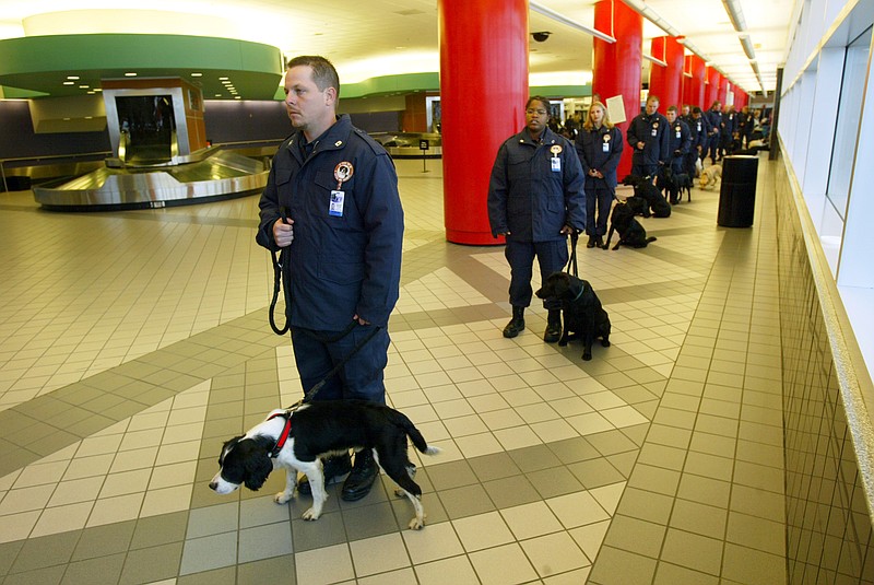 Herman Harper (left) and dog Benji stand in line with other handlers and dogs at then-Little Rock National Airport, Adams Field, Nov. 12, 2004, during a media event to explain the airport's new explosives dogs. (Democrat-Gazette file photo/Staton Breidenthal)