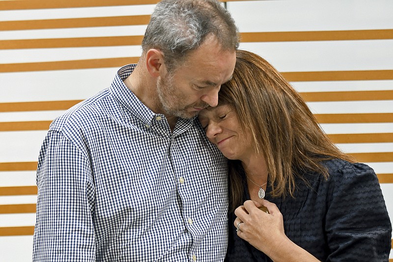 FILE - Simon and Sally Glass comfort each other during an emotional news conference in Denver on Sept. 13, 2022.  Six Colorado law enforcement officers have been charged with failing to intervene during a standoff that ended with the fatal shooting of Christian Glass, a 22-year-old man suffering a mental health crisis last year, prosecutors said Friday, Nov. 17, 2023.(AP Photo/Thomas Peipert, File)