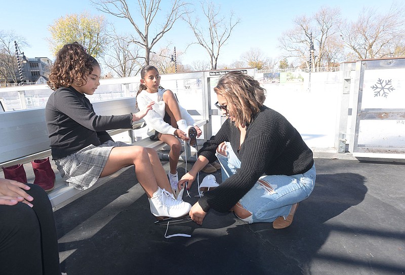 Trashai Brown (right) of Lowell helps her daughters Torrin (left), 7, and Tinley, 8, lace up their skates on Saturday during opening day of the Lawrence Plaza ice rink in downtown Bentonville. The rink is open through Feb. 11 one block north of the Bentonville square. Go to nwaonline.com/photos for todays photo gallery.

(NWA Democrat-Gazette/Flip Putthoff)
