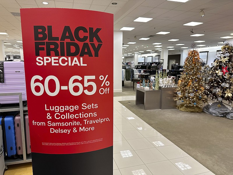 A sign announces Black Friday specials on luggage sets inside a Macy's department store on Monday, Nov. 20, 2023, in Denver. Retailers are kicking off the unofficial start of the holiday shopping season on Friday with a bevy of discounts and other enticements. (AP Photo/David Zalubowski)
