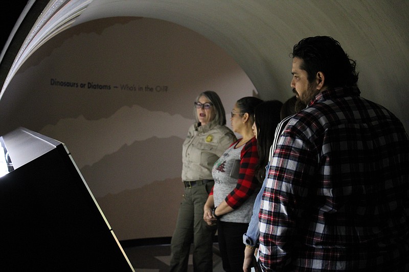 Arkansas Museum of Natural Resources Park Interpreter Paige Creed led a family on a guided tour of the museum on Friday, ahead of a program celebrating the Arkansas State Parks system's centennial anniversary. Here, they're standing in a simulated core shaft, showing the different types of rock and underground formations early oilmen drilled through to find the crude in south Arkansas. (Caitlan Butler/News-Times)