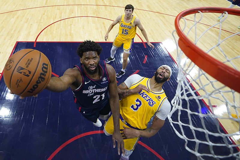 Philadelphia 76ers' Joel Embiid, left, goes up for a shot past Los Angeles Lakers' Anthony Davis during the first half of an NBA basketball game, Monday, Nov. 27, 2023, in Philadelphia. (AP Photo/Matt Slocum)