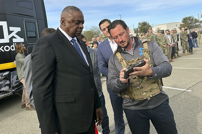 Defense Secretary Lloyd Austin takes a closer look at the device used to control a swarm of drones that lifted off from a parking area at the Defense Innovation Unit in Mountain View, Calif, on Friday, Dec. 1, 2023. Austin is in California for meeting with defense ministers from Australia and the United Kingdom, but took some time to see several projects under development at DIU. (AP Photo/Lolita Baldor)