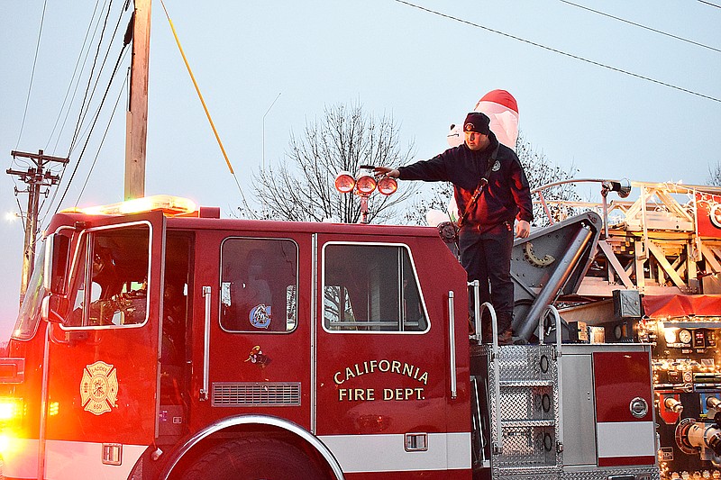 Democrat photo/Garrett Fuller — Kole Ingram, of California Fire Department, stands on top of a ladder truck to adjust lights while Chief Brad Friedmeyer, who is inside the truck, tests the lights Saturday before the start of California's Christmas parade. Ingram said the truck was returned Nov. 20 after getting being refreshed with new graphics.