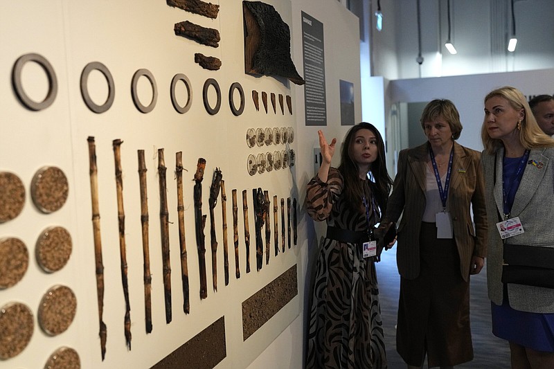 Kadri Simson, European commissioner for energy, looks at a display of the impacts of war at the Ukraine Pavilion during the COP28 U.N. Climate Summit, Monday, Dec. 4, 2023, in Dubai, United Arab Emirates.(AP Photo/Rafiq Maqbool)